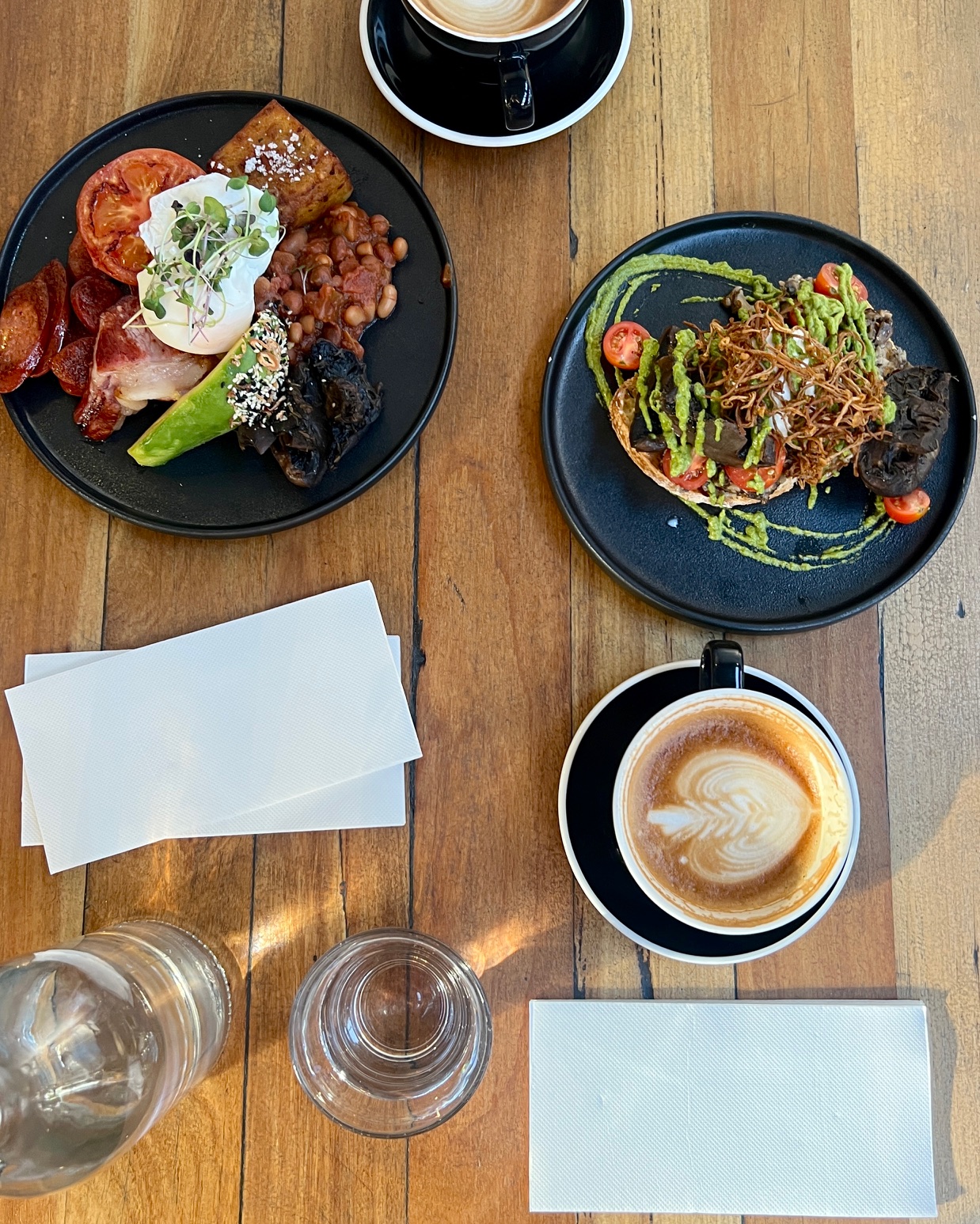 WQDGT Ultrasoft napkins sit on a colourful cafe table with coffee and meals. Ultrasoft napkins add luxury to every hospitality environment